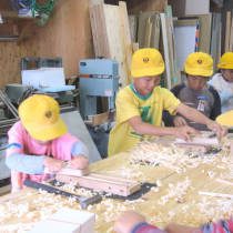 カンナで箸をけずる競争をする児童たち