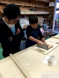 そばを切る子供を見守る父親